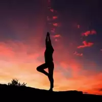 A person practicing yoga at sunset outside.